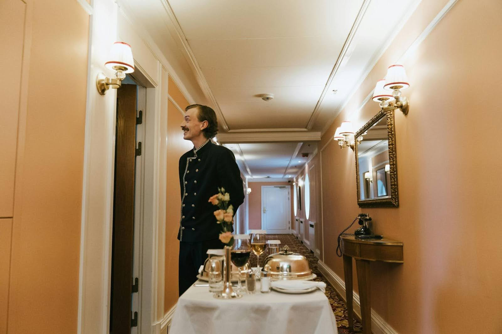 A waiter waiting to serve food at the door of a room