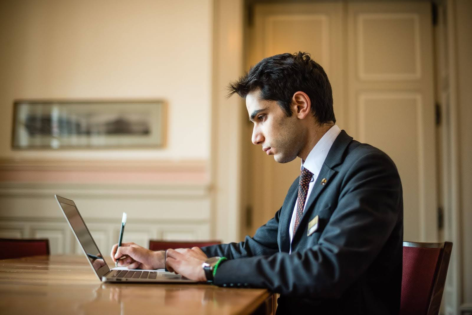 A man in a suit looking at a laptop