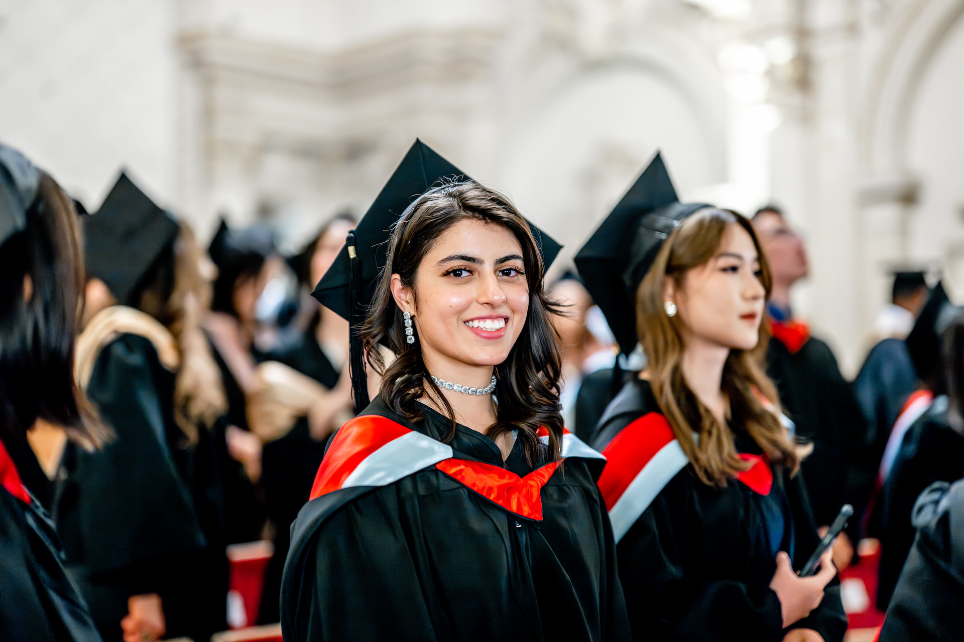 A student with a graduation gown smiling at the camera